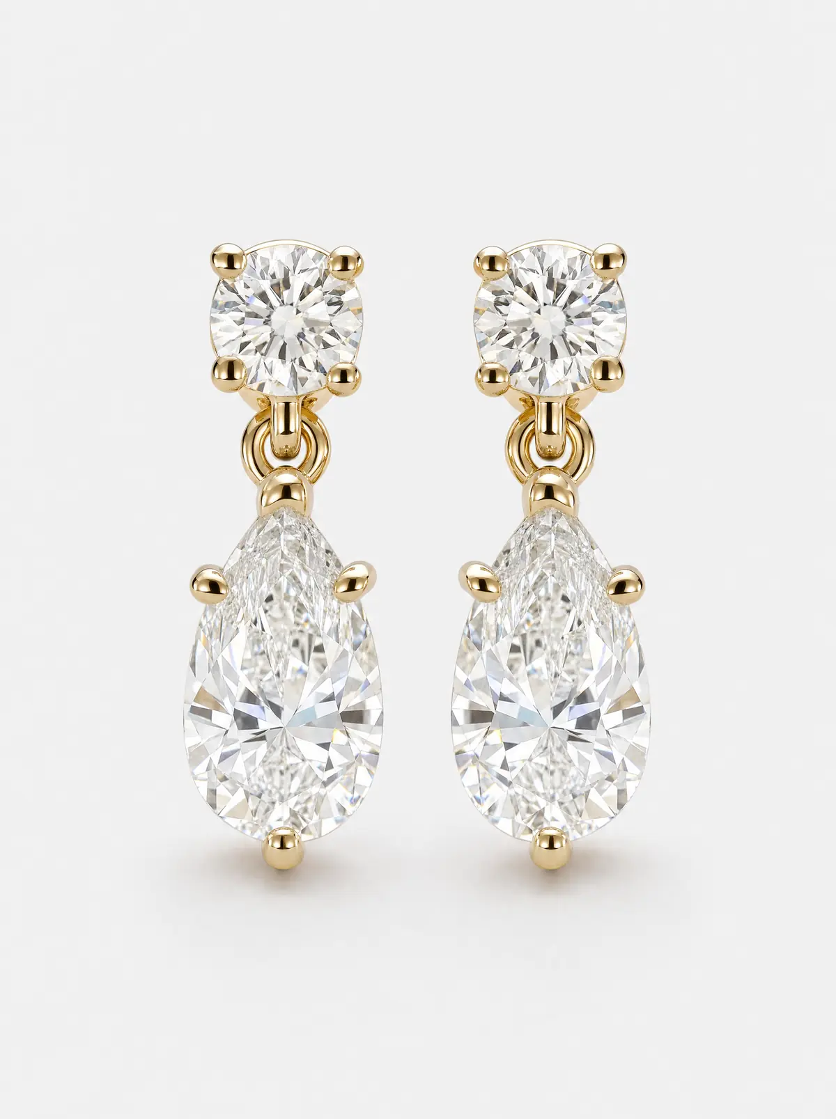 A pair of gold pear-shaped diamond drop earrings on light grey (illustrative, generated)